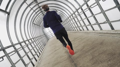 Running Man In Sportswear Workout Before Triathlon, Sprinting In Glass Tunnel. Triathlete Ready For Marathon Hard Training After Running Race Competition. Sport Concept. The camera rotates 360 degrees