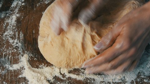 Female hands knead fresh homemade dough on a special kitchen board in the home kitchen. Home baking pastries.