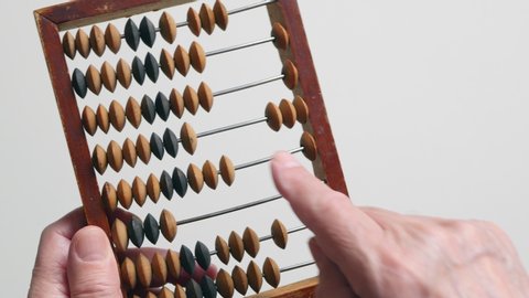 A Elderly Man Is Holding And Moves Wooden Knuckles On A Outdated Vintage Wooden Abacus On A White Background, Close-up On The Left Side.