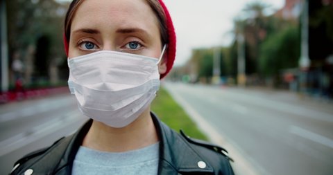 Pandemic Covid-19 coronavirus protection. Portrait of a european hipster woman wearing protective mask street.Concept of health and safety life, N1H1 coronavirus, virus protection.Cinematic Closeup