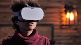 Close-up portrait of mixed race teenager in VR headset shaking off himself and driving away spiders while playing video game. Curly boy feeling full immersion in virtual world using VR goggles