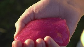 Closeup view 4k video footage of little hand of child holding and squeezing pink transparent slime, sticked to palm.