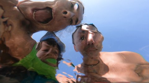  Family with kid having fun at the sea. Distorted faces view through water, underwater view
