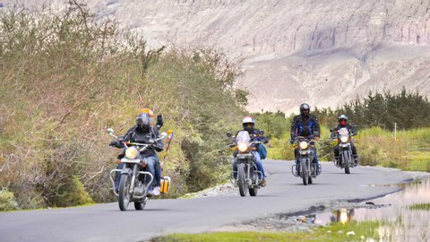 A group of bikers cruising on curvy road through green valley situated in upper Himalaya Mountain in Ladakh, India (August 2019)