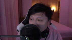 POV webcam view, Chinese male gamer streamer putting on headphones, playing online games and streaming from home. 4K UHD RAW graded footage