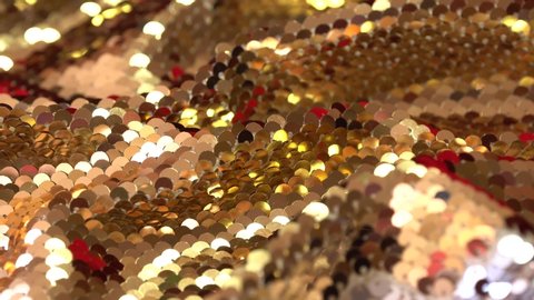Fashion luxury fabric glitter, spangles, paillettes. Gold and red sequin texture. Holiday abstract glitter background with blinking lights