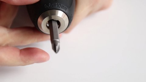 Close up of female hands spins a metal electric screwdriver tool on a white table