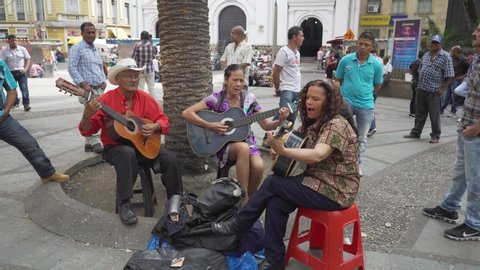 Medellin, Colombia - March 1, 2019:  People man and women guitarist perfomers playing colombian songs on the street in Medellin busy city center