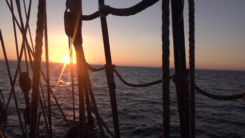 Sunset through the shrouds and rigging of an old sailing ship. Seascape slow motion video.