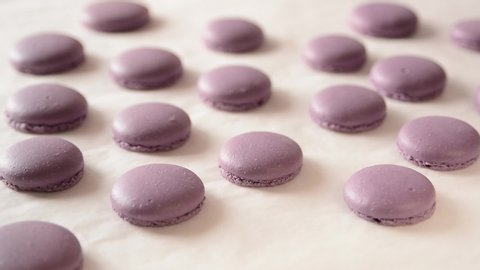 Finished halves of macarons on a tray. French dessert. Close up shot of female baker takes halves of colorful macarons. 