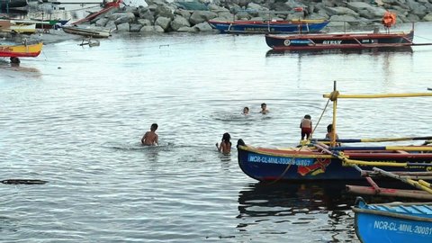 MANILA, PHILIPPINES, February 18, 2020: Several poor children swimming on the polluted shores of Manila Bay. 