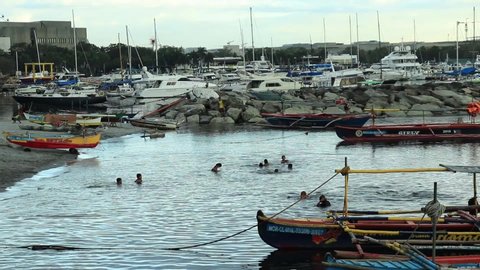 MANILA, PHILIPPINES, February 18, 2020: Several poor children swimming on the polluted shores of Manila Bay. 