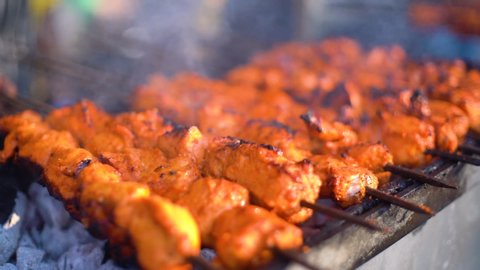 Paneer fish chicken tikka roasting on an open hearth with glowing coals and smoke coming out. A staple of indian cusine as a starter or with roti naan bread and a very spicy marination. North indians