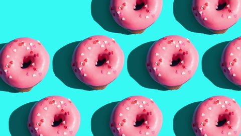 Pink glazed donut motion pattern on blue background. Creative concept