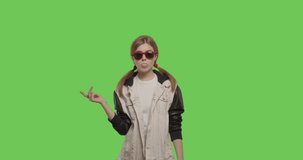 Young pretty girl wearing jacket chewing bubble gum over green screen background, Woman in suglasses having fun on chroma Key . 4k raw video footage slow motion 60 fps