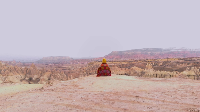 woman sitting at the edge of the cliff and watching Fairy chimneys in lovers hill in Cappadocia