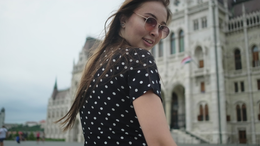 traveller girl is running on square in front Hungarian Parliament building, smile and enjoy