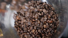 Beans of Coffee Raining in Slow Motion. Conceptual clip of coffee beans, close up. Coffee beans pouring into glass bowl on coffee machine. Top view. grinding machine. Full hd
