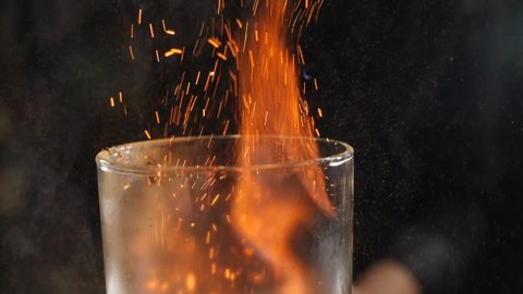 Slow motion cocktiail video of barmaid sprinkling cinnamon over flaming beverage. Bartender pours cinnamon powder to flame of sambuca cocktail, flaming cocktail, alcohol drink, bar party. Full hd