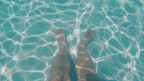 Men's feet at the bottom of the pool