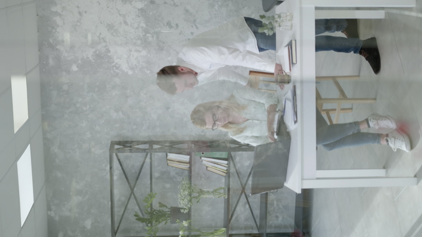 happy office employees discussing work at desk with laptop computer then give each other high five in a white modern room, vertical screen