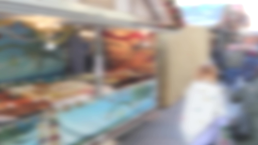 Abstract blurred shoppers customers walking past a street food stall