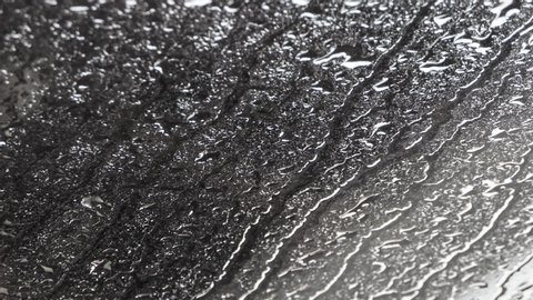 rain falls heavily on the window forming many droplets of water