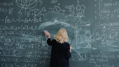 Slow motion of crazy female scientist writing formulas on chalk board talking gesturing solving scientific problem. People and occupation concept.