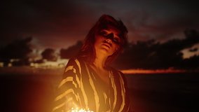 Close up portrait of young beautiful woman at sunset on the beach. Pretty girl posing for camera with sparklers at sunset. Femininity concept. City people travel. Business woman at summer vacation.