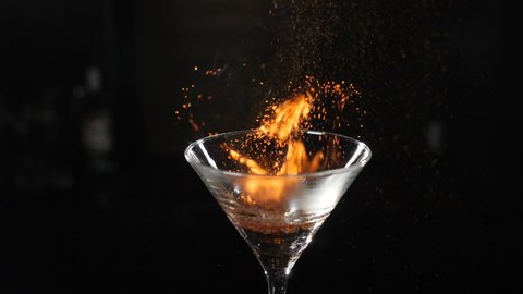 Slow motion cocktiail video of barmaid sprinkling cinnamon over flaming beverage. Bartender pours cinnamon powder to flame of sambuca cocktail, flaming cocktail, alcohol drink, bar party. Full hd