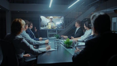 Executives, Businesspeople, Investors and Management Team Sitting at Conference Table Talking on Video Call with Factory Chief Engineer. Production Increase, Record Growth. Late Night In Meeting Room