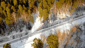 aerial video of a railway in a snow-covered forest with a large number of coniferous trees on a Sunny day. the camera rotates clockwise
