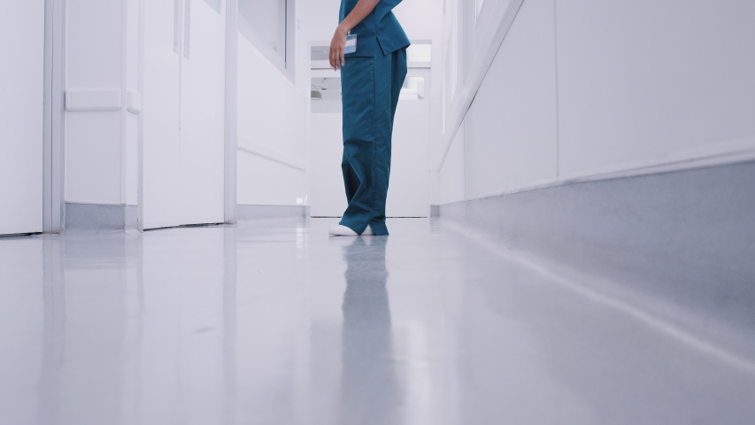 Stressed and overworked female doctor wearing scrubs sitting on floor in hospital corridor - shot in slow motion Royalty-Free Stock Footage #1046910592