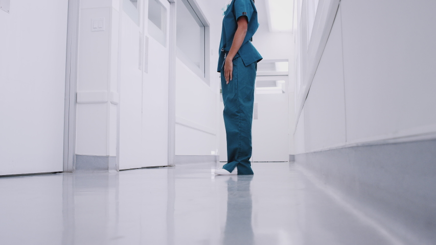 Stressed and overworked female doctor wearing scrubs sitting on floor in hospital corridor - shot in slow motion Royalty-Free Stock Footage #1046911822
