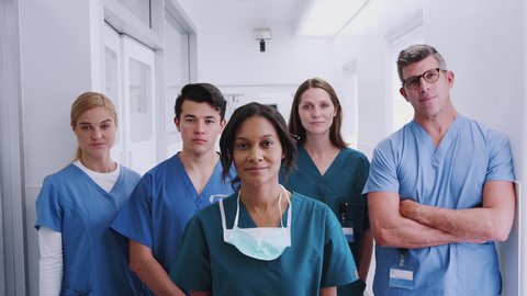 Portrait of smiling multi-cultural medical team standing in hospital corridor - shot in slow motion
