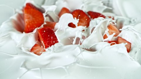 Super Slow Motion Shot of Fresh Strawberries Falling into Cream at 1000fps.