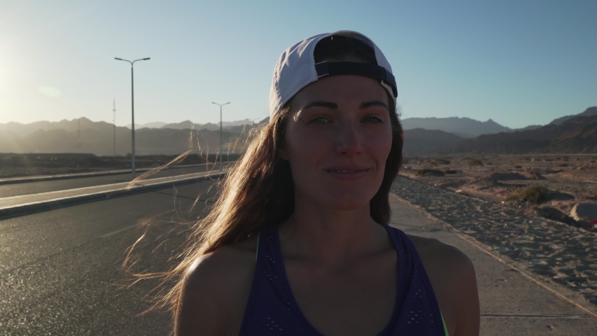 Girl smiling to camera standing in highway in mountains sunset rapid slow motion