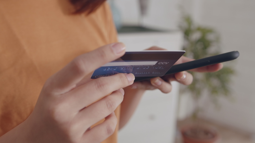 Young Asian Woman hand holding credit card using a digital mobile device and Buying online, internet shopping. Close-up Asian Female hand typing bank card number into a smartphone.Lifestyle Concept. Royalty-Free Stock Footage #1046915872