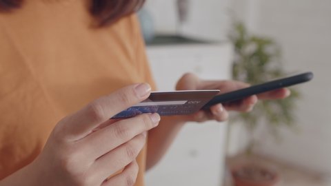 Young Asian Woman hand holding credit card using a digital mobile device and Buying online, internet shopping. Close-up Asian Female hand typing bank card number into a smartphone.Lifestyle Concept.