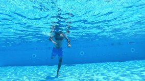 Handsome man diving into the water of the pool. Man swimming underwater in the clear water of the swimming pool. Healthy lifestyle.