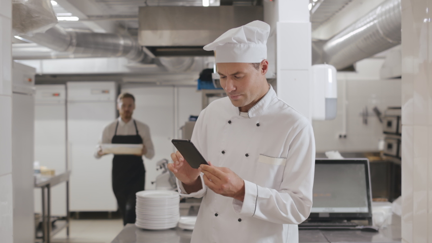 Male head chef with smartphone at commercial kitchen during break. Portrait of handsome kitchen employee receiving order on smartphone. Cooking, profession and people concept - Powered by Shutterstock - Get 15% off with code: PIKWIZARD15