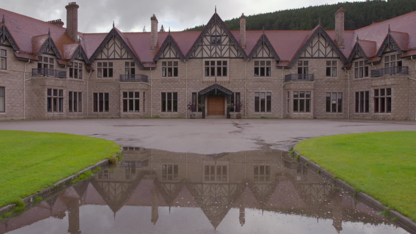 Medium low angle still shot of reflections of Mar Lodge Estate accommodation buildings on front pavement path, National Trust of Scotland, Braemar, Scotland, UK