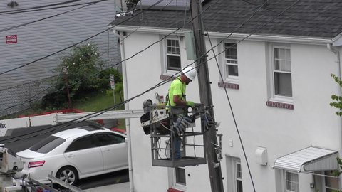 Utility electrical city worker uses truck bucket boom lift to reach telephone pole top, Revere Massachusetts USA, June 18, 2019