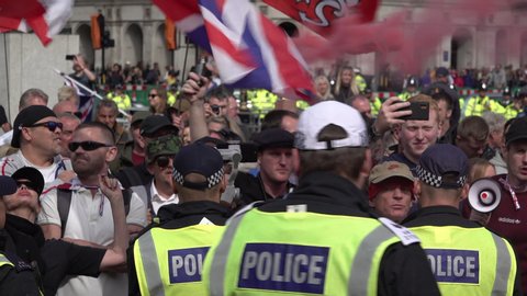London / United Kingdom (UK) - 09 07 2019: Police officers watch angry Brexit protestors letting of a red smoke flare