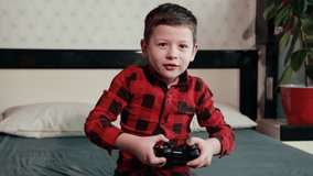 cute boy in black red shirt is playing video game, holding joystick, having an emotional time