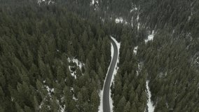Flight over the winter mountains with road serpentine and snowy forest. Top down view. UHD 4k drone video