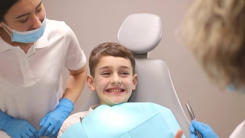 A little boy treats his teeth, two dentists examine the child's teeth, concepts about dentistry
