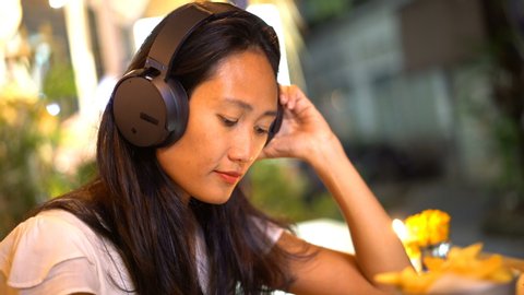 Young, happy woman listening to music on smartphone in the cafe