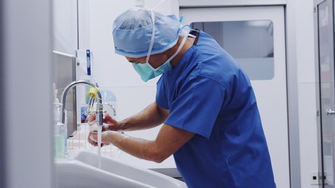 Male surgeon wearing scrubs washing hands before hospital operation - shot in slow motion วิดีโอสต็อก