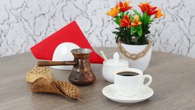 Coffee cup with bun and coffee pot with flowers in pot on spinning wooden table background. FHD.